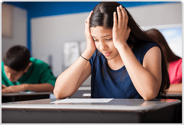 A teen sitting at a desk with her head in her hands